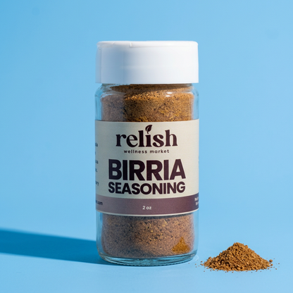 A 2 oz clear plastic bottle of Relish Wellness Market Birria Seasoning with a white cap, set against a solid light blue background with a small pile of the brown seasoning powder next to it.