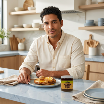 Man at a kitchen counter enjoying toast with Bourbon Citrus Honey by Relish Market.