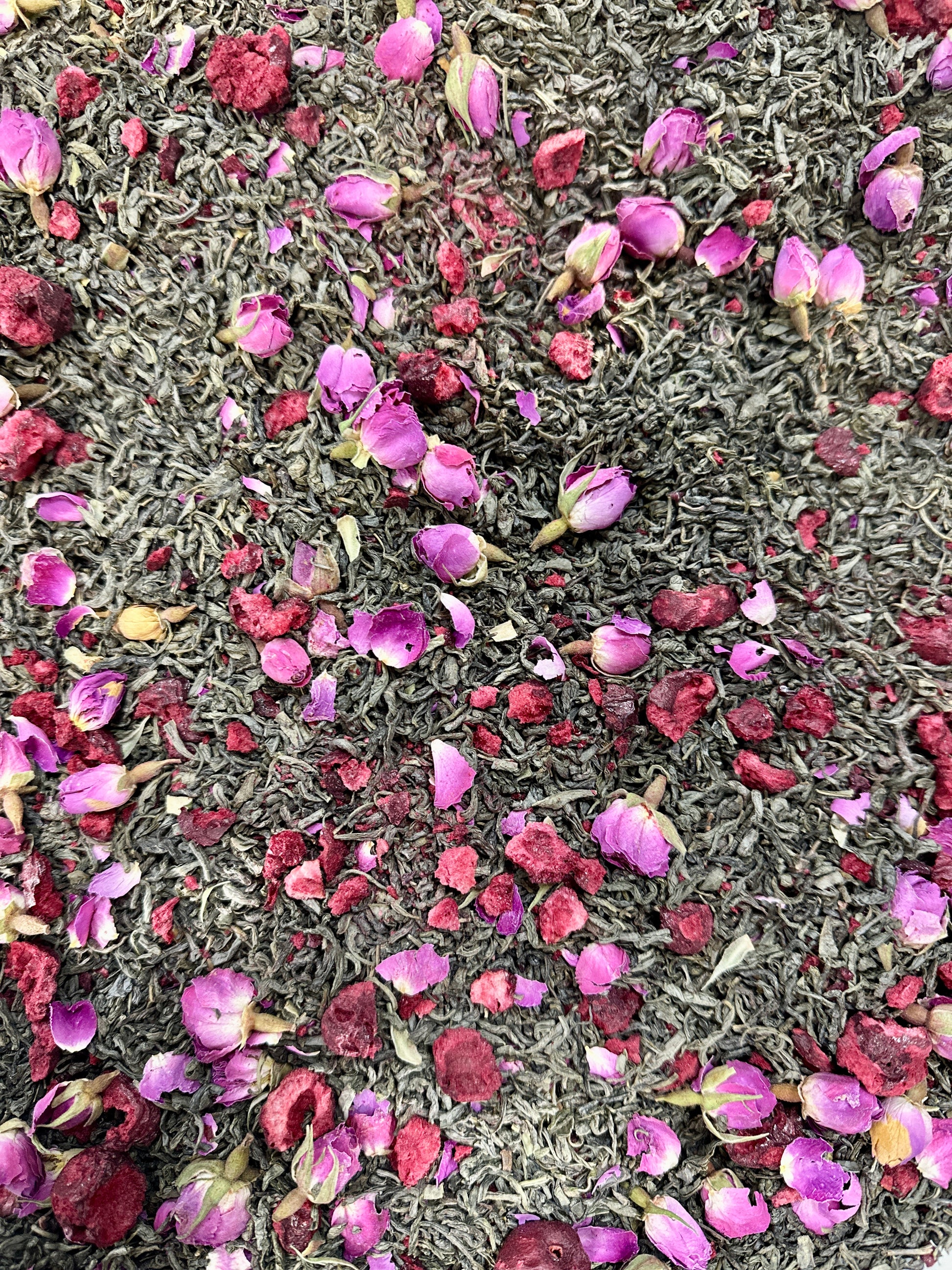 Cherry Blossom Tea blend with dried pink rose flowers and leaves, dried cherries and green tea leaves as the background 
