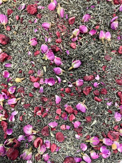 Cherry Blossom Tea blend with dried pink rose flowers and leaves, dried cherries and green tea leaves as the background 