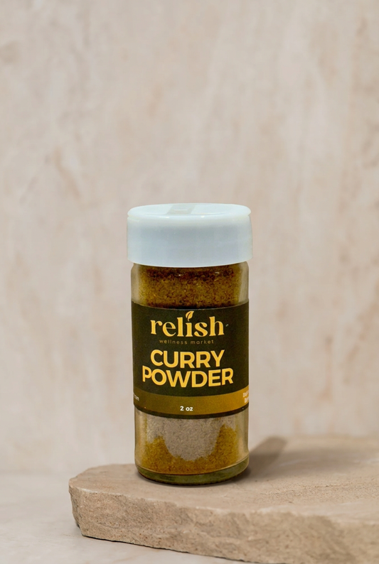 A 2 oz bottle of Relish Market Curry Powder resting on a textured stone slab against a neutral beige background.