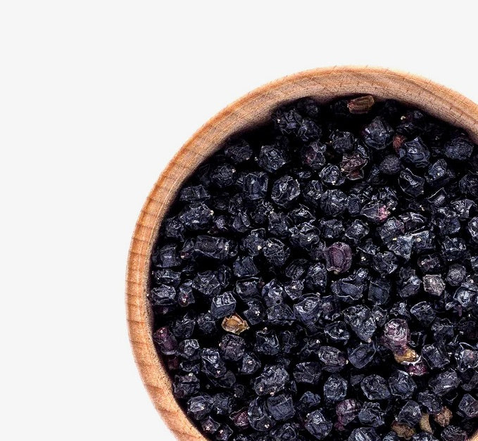 A wooden bowl of dried elderberries by Relish Market on a white background.
