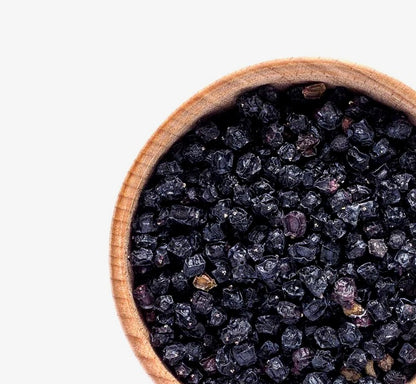 A wooden bowl of dried elderberries by Relish Market on a white background.