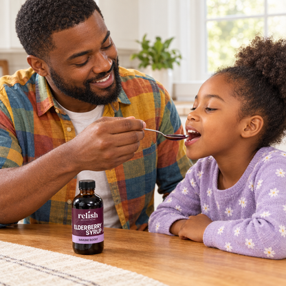Black father offering his child a spoonful of elderberry syrup by Relish Market