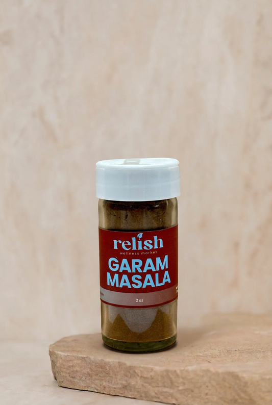 A bottle of Relish Market Garam Masala spice blend on a stone slab against a neutral beige background.
