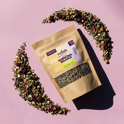 Kraft bag of Hormonal Balance Tea Blend by Relish Market on a pink background surrounded by its loose botanical blend