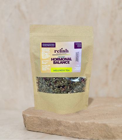 Kraft Bag of Relish Market Hormonal Balance Wellness Tea on a stone slab and neutral background.