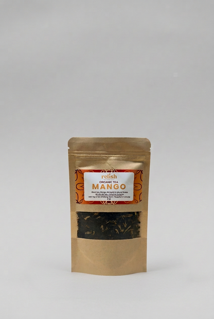 A stand-up kraft paper pouch of Relish Market's Organic Tea Mango, featuring a clear window that displays the dark tea leaves inside, set against a neutral light gray background.