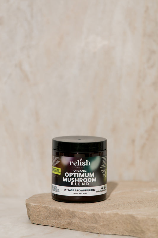 A jar of Optimum Mushroom Powder by Relish Market sits on a rustic stone slab set against a beige textured background.