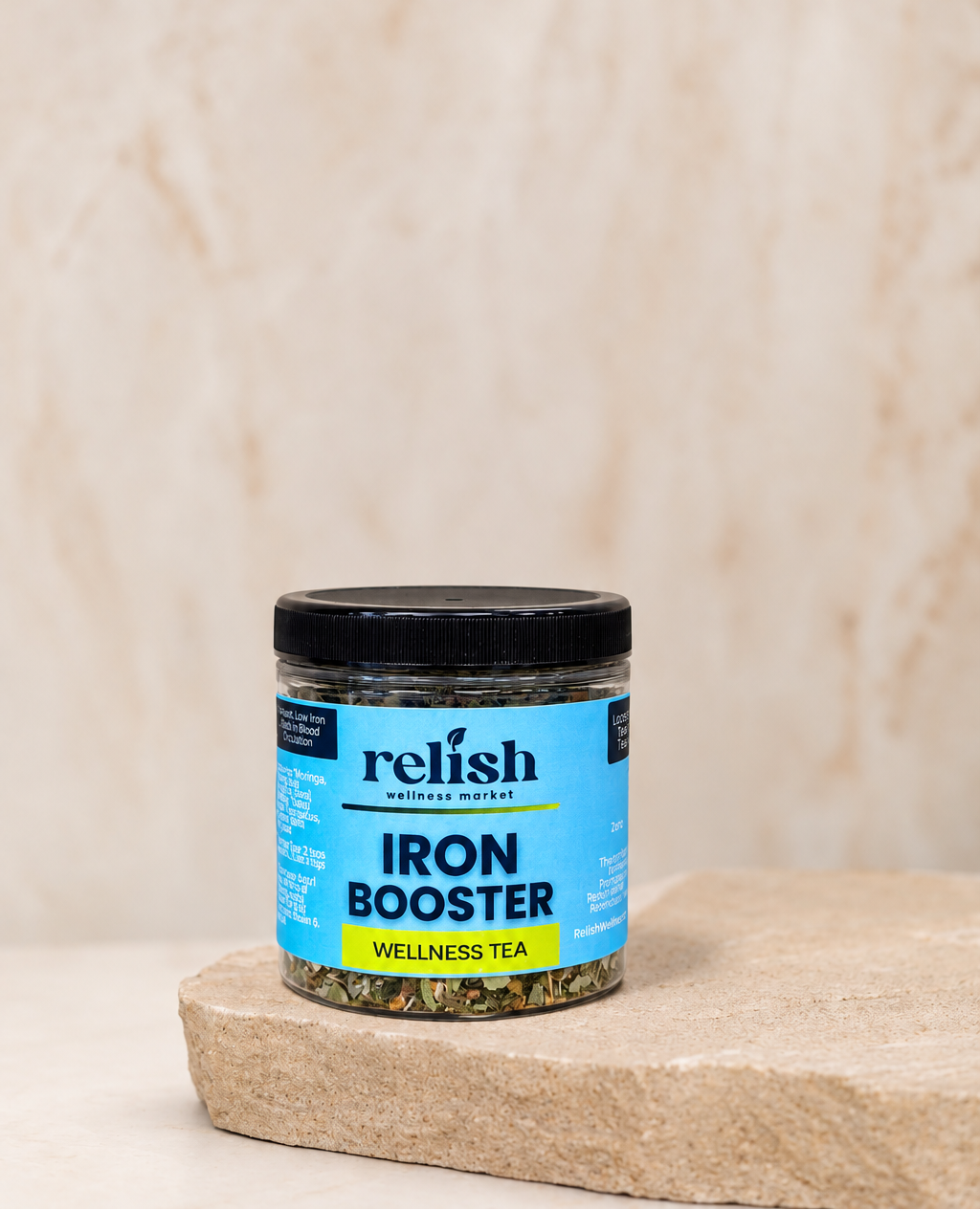 A jar of Relish Wellness Market Iron Booster tea sits on a rustic stone slab against a textured beige background.