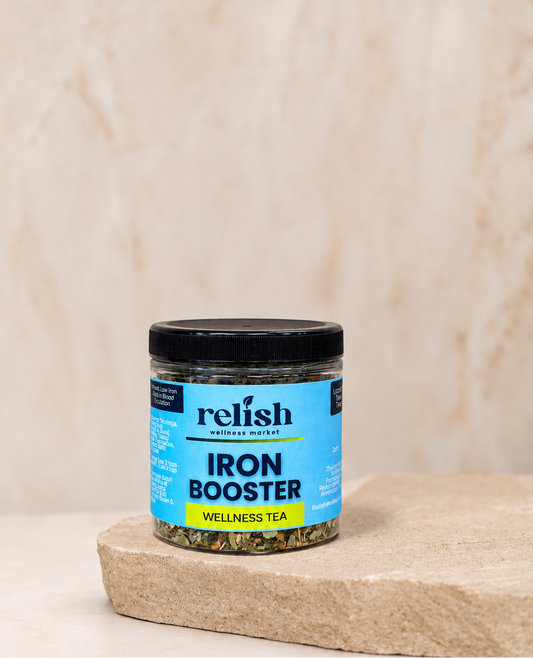 A jar of Relish Wellness Market Iron Booster tea sits on a rustic stone slab against a textured beige background.