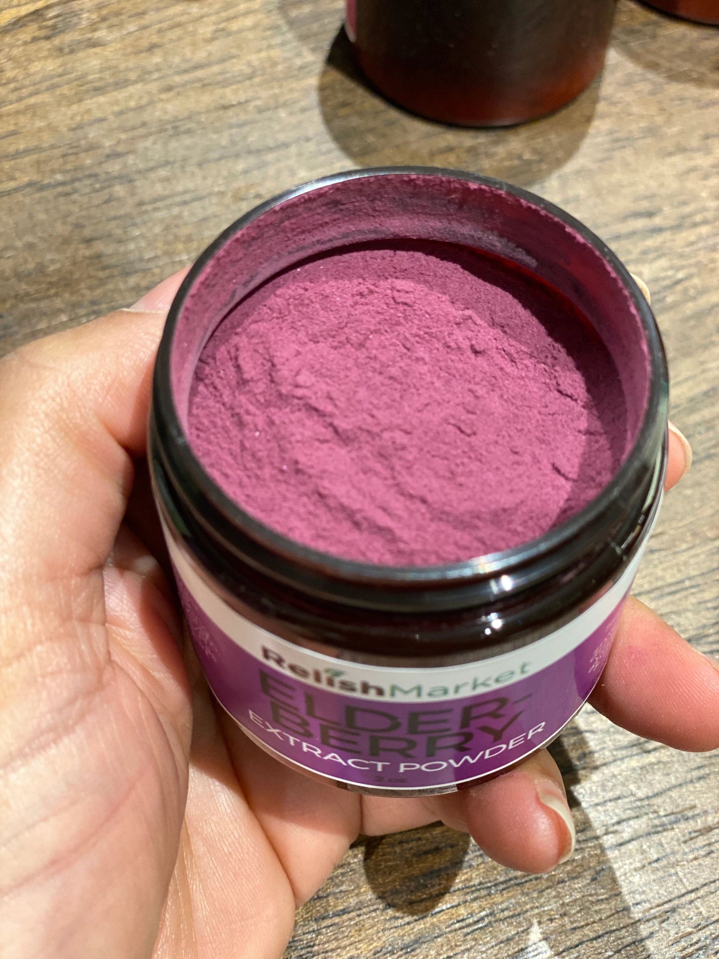 Relish_market_Elderberry Extract Powder hand holding open jar