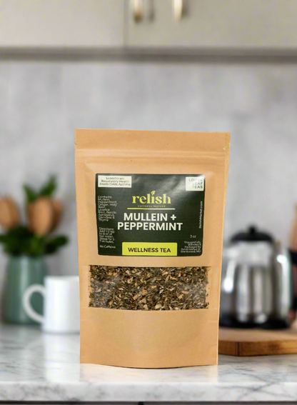 Kraft zip bag of Relish Market mullein & peppermint tea on a marble kitchen counter with a white tea cup and a silver tea kettle in the background.