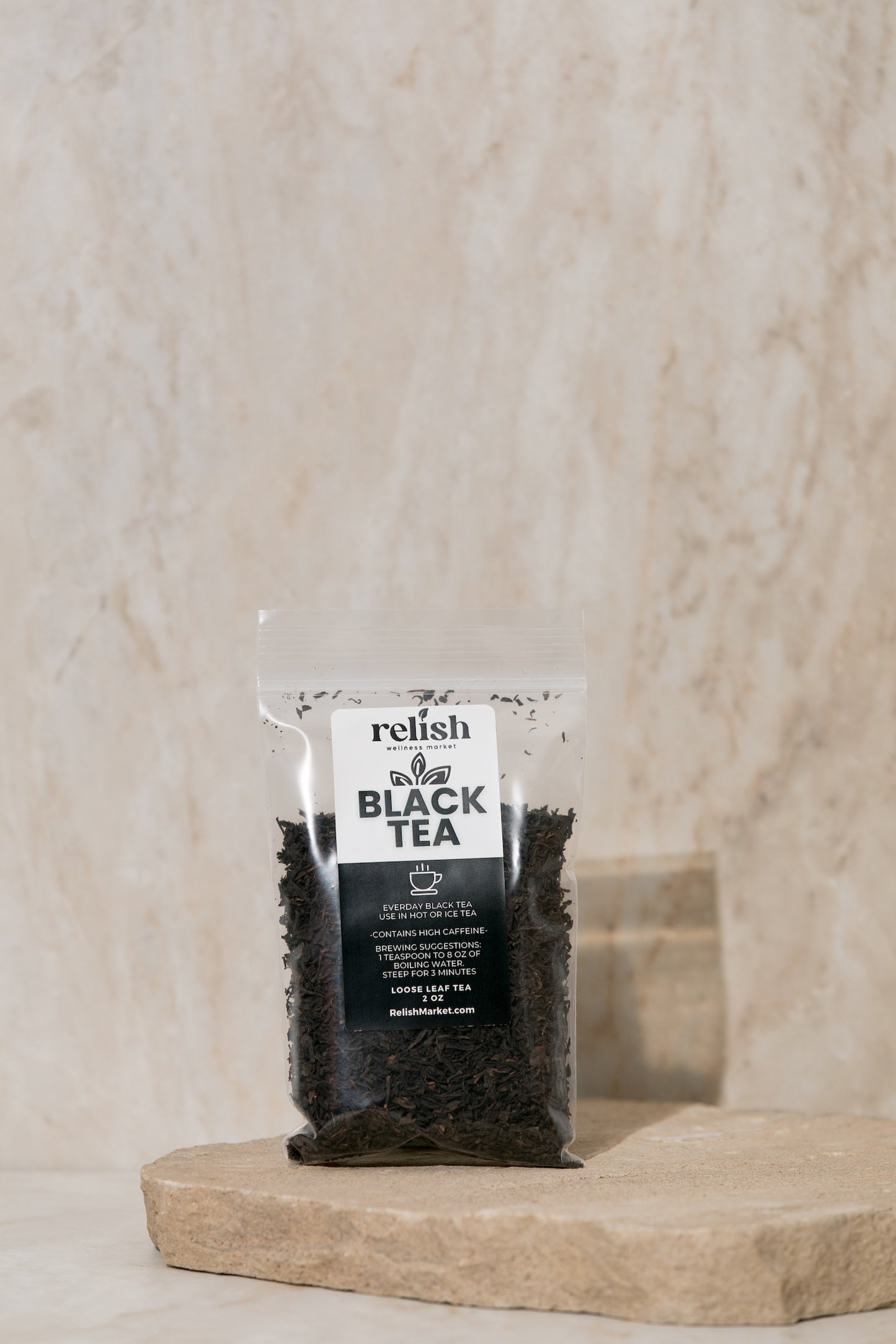 Packaged black tea on a stone slab with a neutral background