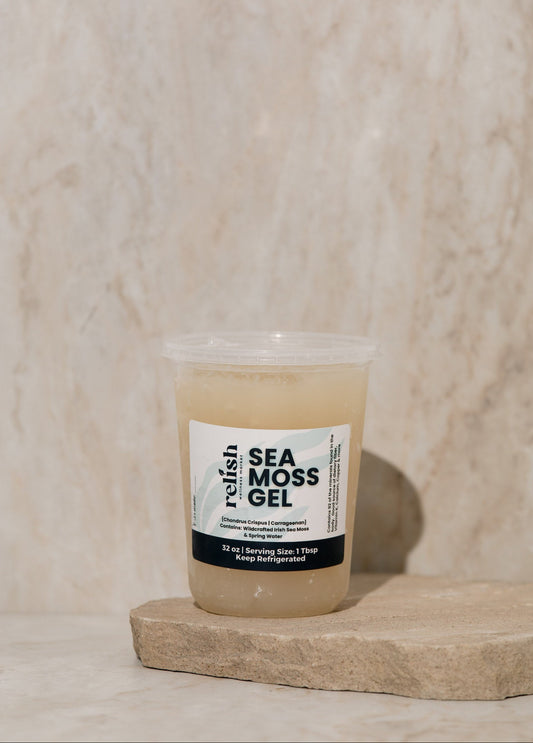 Clear container of Sea Moss Gel with a label on a wooden surface set against a beige textured background.