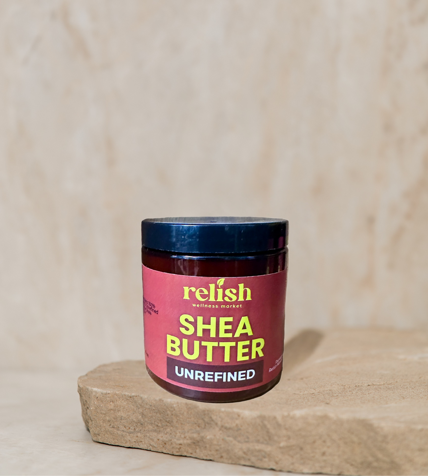 Jar of unrefined shea butter with 'relish' branding on a wooden surface.