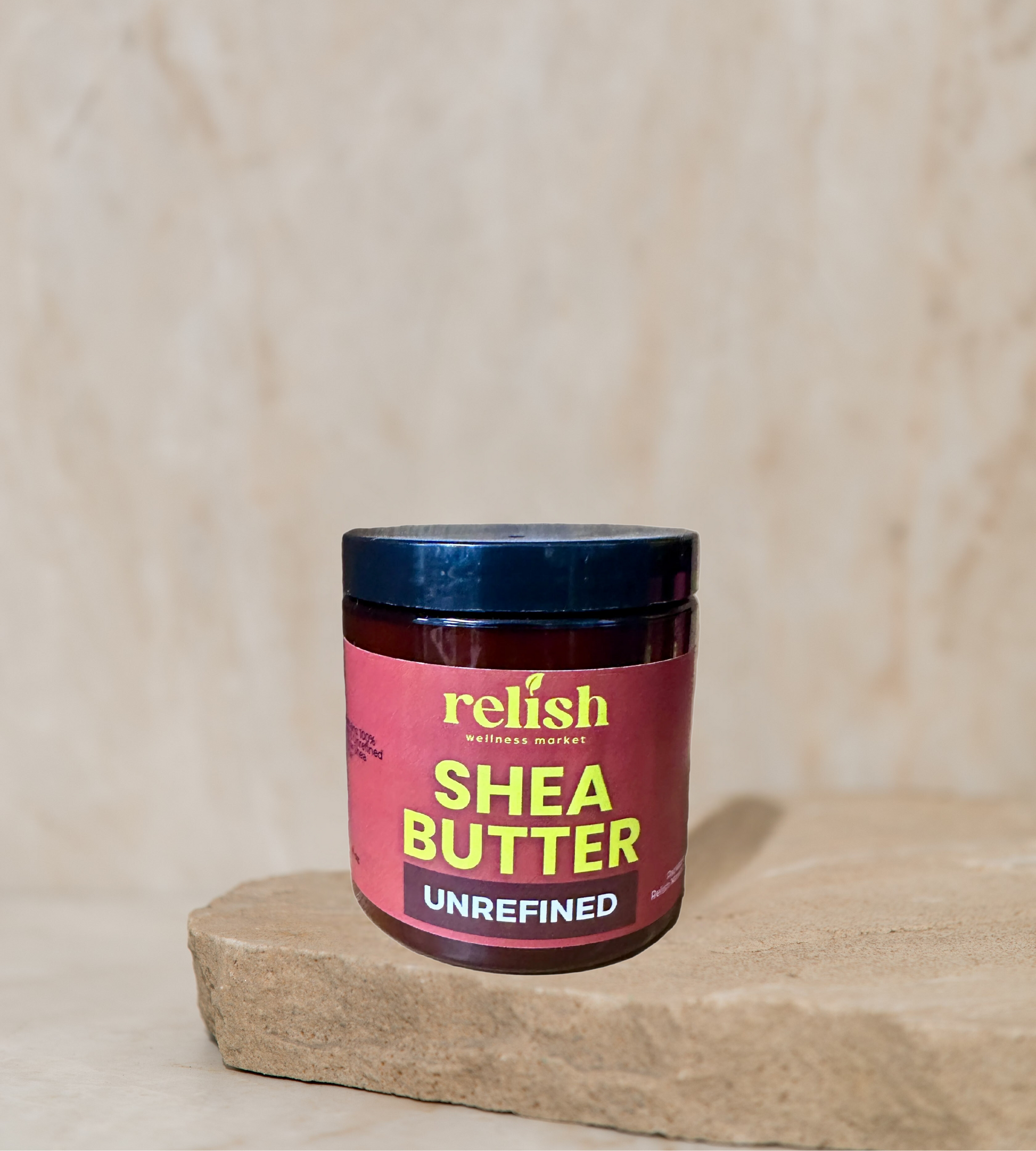 Jar of unrefined shea butter with 'relish' branding on a wooden surface.