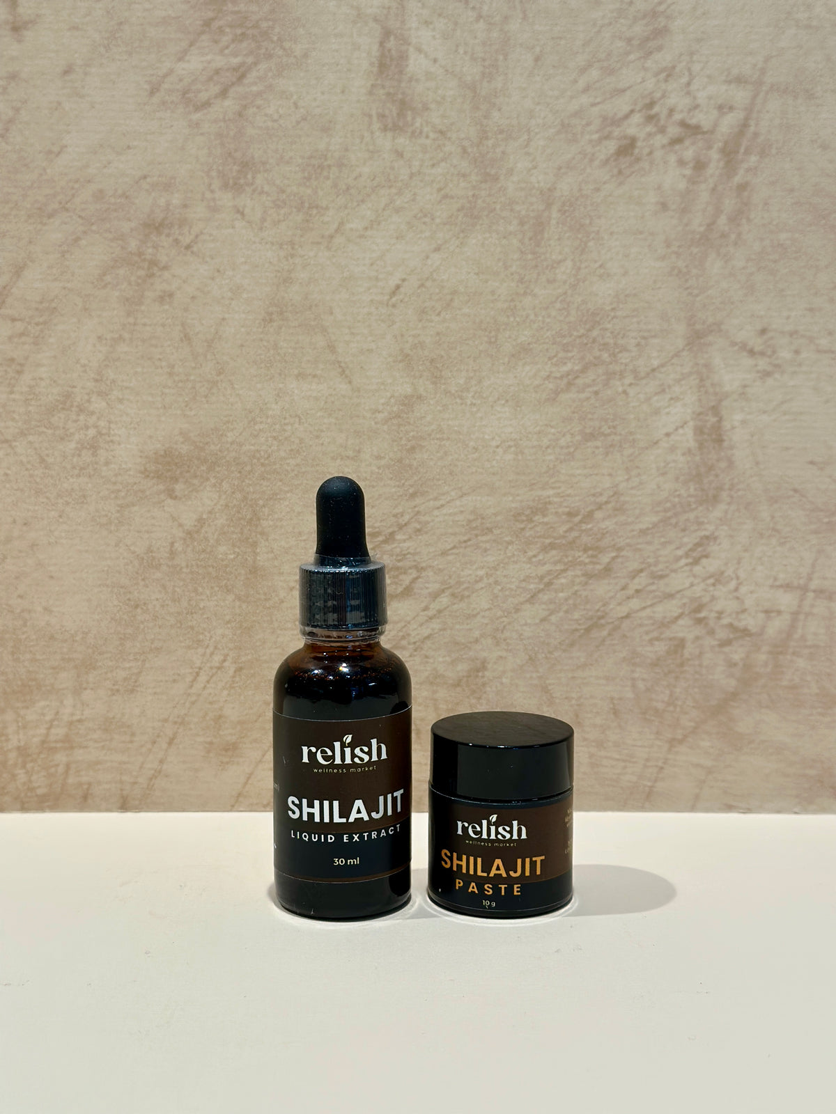 A small jar of Shilajit Paste and jar of Shilajit Drops by Relish Market on a neutral background.
