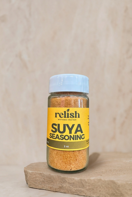 A bottle of Relish Market Suya Seasoning placed on a stone slab against a neutral beige background.