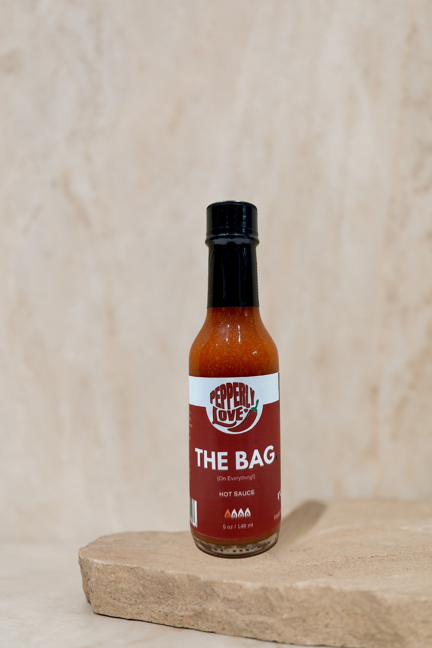 Pepperly Love Large The Bag Hot Sauce jar sitting on a rock slab