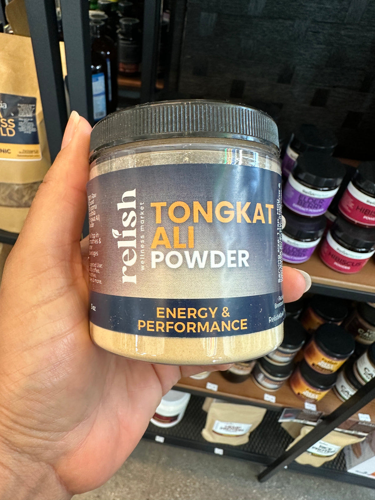 A hand holding a jar of Tongkat Ali Powder by Relish Market